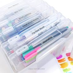 several markers and pens are in a plastic container