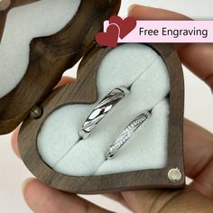 two wedding rings in a heart shaped box that is open to show the ring inside