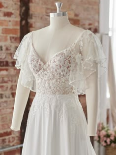 the back of a wedding dress on display in front of a brick wall and window