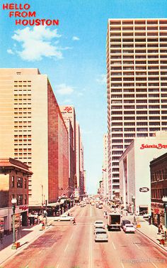 an old photo of a city street with tall buildings and cars driving down the road