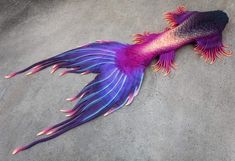 a purple and pink fish laying on the ground