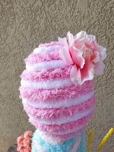 there is a pink flower on top of a stack of blue and white fluffy cakes