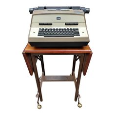 an old fashioned typewriter sitting on top of a wooden table with wheels and casteors