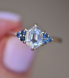 a close up view of a ring with an emerald cut diamond and blue sapphire stones