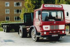 a red and white truck parked in front of a brick building next to a green tree