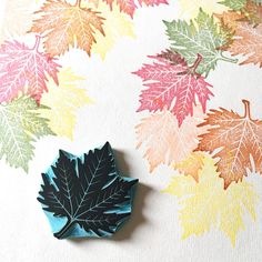 a leaf shaped object sitting on top of a table next to a wallpaper covered in leaves