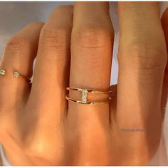 a woman's hand with two gold rings on it and one diamond ring in the middle