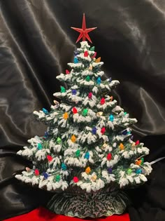 a small white christmas tree with multicolored lights on it's base and a red star