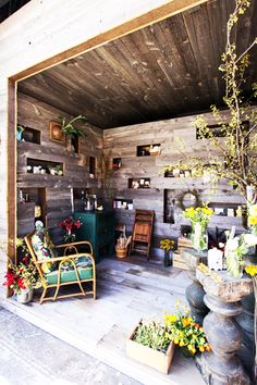 the inside of a wooden building with lots of potted plants and flowers in it