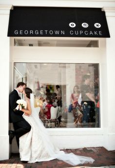 a bride and groom kissing in front of a store