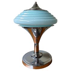 a blue glass table lamp sitting on top of a metal base