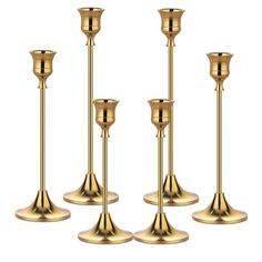 four gold candlesticks are lined up against a white background