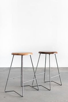 two stools sitting next to each other in front of a white wall and floor