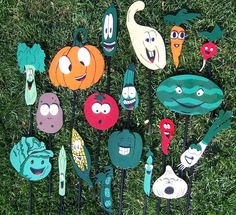 a group of different colored vegetables on top of green grass with faces painted on them