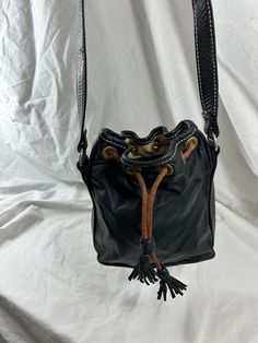 a black leather purse with tassels and handles