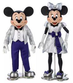 two mickey and minnie mouse figurines standing next to each other on metal bases