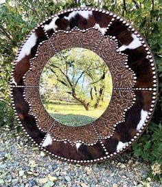 a round mirror sitting on top of a gravel ground