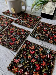 four coasters with flowers on them sitting next to a coffee cup