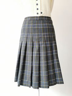 Vintage Wool Above the Knee Checked Skirt from the 1970's. High Waisted wool checked skirt in gray, blue, yellow and green. The skirt has a zipper and button closure at the left side. There is no lining. Length is above the knee. Material: Pure Virgin Wool Made in Italy Size: Sizes Marked on the label - 40 Italian, French - 38, German - 36, GB 10, US Numeric 6 Approximate measurements (taken while skirt is lying flat, double waist and hips): Waist (double that): 12.5 inches / 31.7 cm Hips (doubl Fitted Knee-length School Skirt, School Fitted Knee-length Skirt, Fitted Knee-length Skirt For School, Retro Skirted Bottoms For School, Classic Green Pleated Skirt, Retro Pleated Skort, Vintage Mini Skirt For School, Yellow Plaid Skirt, Plaid Midi Skirt