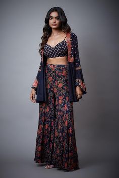 Navy blue tie-up top with floral embroidery and bell sleeves. Paired with printed, embroidered palazzo and blouse.
Component: 3
Pattern: Printed,Embroidered
Type Of Work: Floral
Neckline: Blouse: V neck
Sleeve Type: Top: Bell Sleeves
Fabric: Rayon Crepe
Color: Blue
Other Details: 
Tie-up top
Printed palazzo
Occasion: Sangeet - Aza Fashions Bohemian Long Sleeve Palazzo Set, Bohemian Long Sleeve Floral Print Sharara, Bollywood Style Festive Pant Set With Floral Print, Bollywood Style Festive Floral Pant Set, Bollywood Style Festive Floral Print Pant Set, Bohemian Designer Sharara For Spring, Floral Print Sharara With Long Sleeves For Spring, Bohemian Palazzo Set With Resham Embroidery And Long Sleeve, Festive Bollywood Pant Set With Floral Print