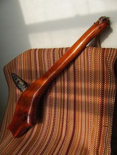 an old wooden instrument sitting on top of a striped couch cushion in the sun light