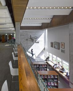 the inside of a library with people sitting at tables and reading books on their desks