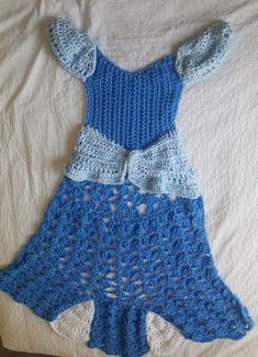 a crocheted blue dress laying on top of a bed