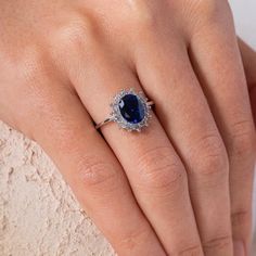 a woman's hand with a ring on it and a blue stone in the middle