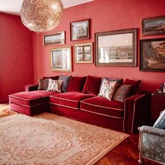 a living room with red walls and pictures hanging on the wall above the couches