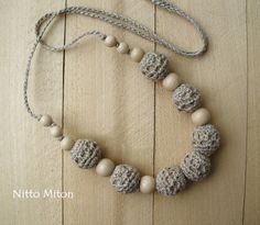 a crocheted necklace is displayed on a wooden surface