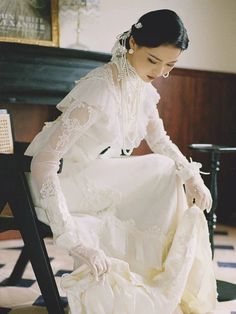 a woman in a white dress sitting on a chair