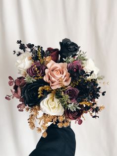 a vase filled with flowers on top of a white table next to a black cloth