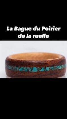 a wooden bracelet with turquoise stones inlayed to it's sides and the words la bague du polier de la tu centre