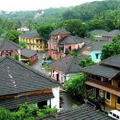 an aerial view of some houses in the mountains with trees and hills in the background