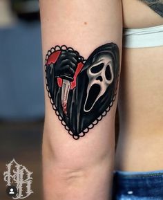 a woman's arm with a tattoo on it that has a heart shaped mask in the shape of a ghost