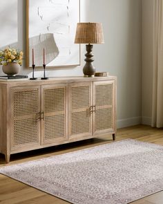 a living room with a rug, lamp and wooden cabinet