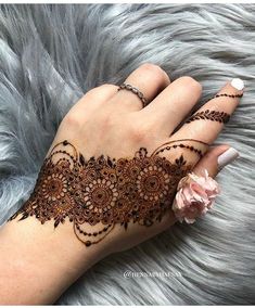 a woman's hand with henna tattoos on it and flowers in the middle