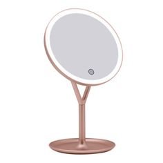 a round mirror on a stand with a light in the middle and a white background