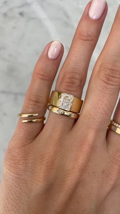 a woman's hand with three different rings on her fingers and one has a diamond in the middle