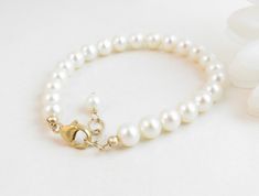 "A classic real freshwater pearl bracelet for newborn, infant, baby, child, little girl, tween or teen. This keepsake bracelet is created with Grade-A 5.5mm round freshwater pearls and a 14K gold-filled oval lobster clasp with a 1/2\" \"Grow with Me\" extender chain. Arrives packaged in my signature high-quality reusable canvas gift bag. Beautiful and ready for gift giving. S I Z I N G . G U I D E The bracelet should be 3/4\" larger than her snug wrist measurement. If you are unable to measure, Classic Adjustable Hypoallergenic Pearl Bracelet, Classic Adjustable Pearl White Bracelet, Adjustable Classic Pearl Bracelet For Anniversary, Classic Adjustable Pearl Bracelet For Anniversary, Classic Pearl Bracelet With Extender For Gift, White Pearl Charm Bracelet For First Communion, White Hypoallergenic Pearl Bracelet For First Communion, Elegant Pearl Rosary Bracelet For Baptism, Classic Adjustable Jewelry For First Communion