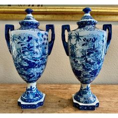 two blue and white vases sitting on top of a wooden table next to each other