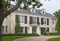 a large white house with black shutters and trees