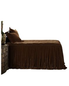 a bed with brown sheets and pillows on it's headboard next to a dresser