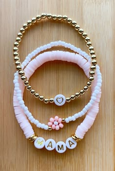 three bracelets with charms on top of a wooden table