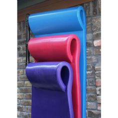 three different colored yoga mats hanging on a brick wall