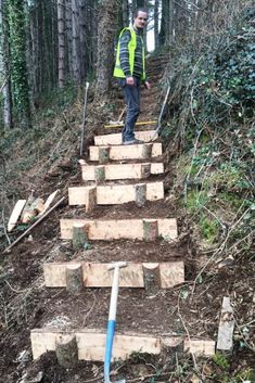 a man is standing on some steps in the woods with tools and wood planks