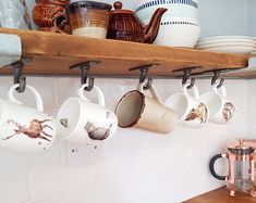 coffee mugs are hanging on the wall in this kitchen