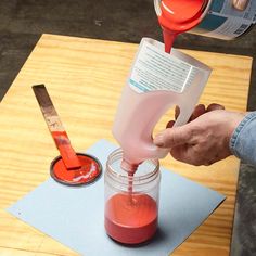 someone is pouring red liquid into a jar