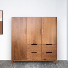 a large wooden cabinet sitting next to a wall with a painting hanging on the wall