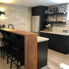 a modern kitchen with black cabinets and white brick wall, bar stools in the center